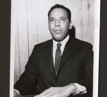 Black and white photograph of Howard Moore Jr. seated at desk.