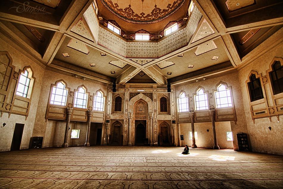 Interior of Al-Farooq Masjid of Atlanta, depicting a detailed carpet, window archways, and a central dome.