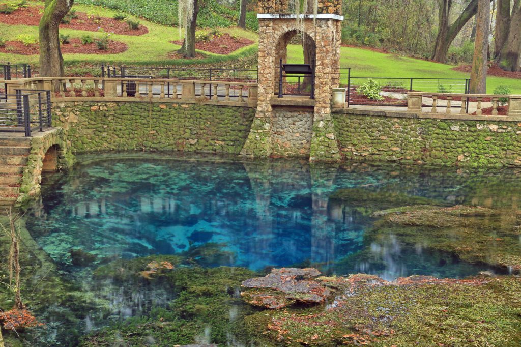 Radium Springs, one of Georgia's Seven Natural Wonders, is depicted, showcasing its crystal clear water and surrounding pathways walkways.